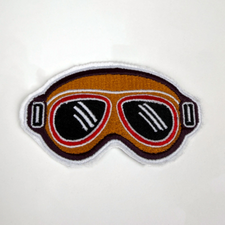 Embroidered Racing Relics patch shaped like vintage racing goggles.
